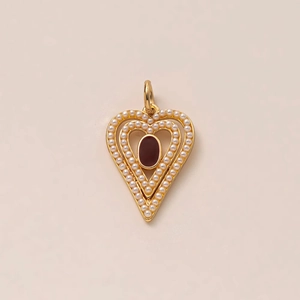 Detail of gold heart pendant with white pearls and a deep red gemstone center