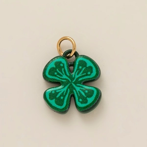 Detalle del colgante de trébol verde con purpurina y aro de metal dorado pulido
