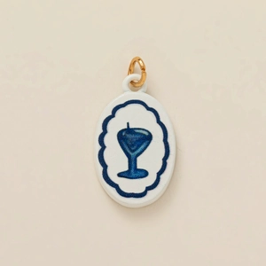 Detailed macro view of an oval ceramic pendant with blue cocktail pattern and gold ring