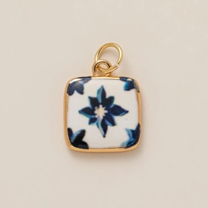 Detail of square ceramic pendant with blue floral pattern and gold metal frame