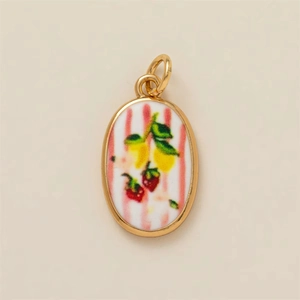 Detalle macro del colgante ovalado con motivos de limón y fresa en esmalte a rayas