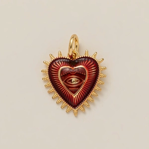 Detail van een hartvormige hanger met rood emaille oogmotief en gouden stralende randen