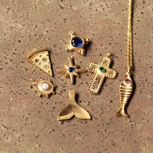 Set of 18K gold-plated stainless steel charms with colorful stones on a textured background