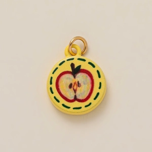 Close-up of a yellow round apple pendant charm with a gold-colored metal hanging ring