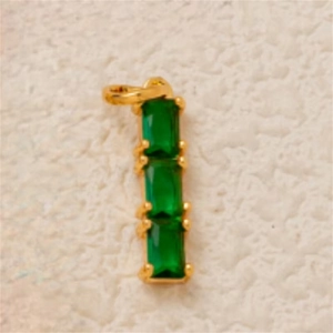 Close-up of three emerald green rectangular gems set in vertical gold-plated prongs
