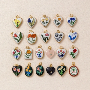Flat lay of vintage enamel pendants with hand-painted floral motifs and gold metal edges