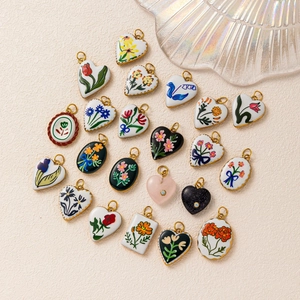 Detailed close-up of floral enamel charms with gold edges and rose tulip patterns