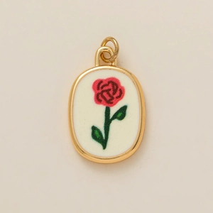 Gros plan du pendentif ovale doré avec motif de rose rouge sur fond blanc pur
