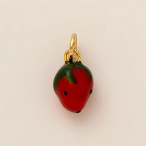 Close-up of strawberry-shaped charm with vibrant red enamel and golden metal loop