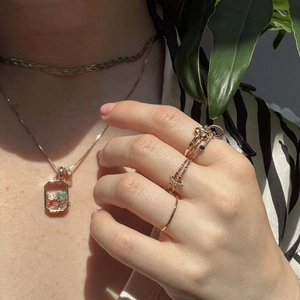 Gros plan d'un collier médaillon en or 18 carats avec pendentif transparent et micro charms