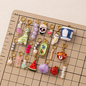 Assorted stainless steel colorful skull and animal charms on a grid mat background