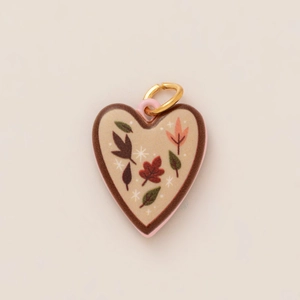 Macro detail van hartvormige hanger met herfstbladpatronen en gouden verbindingsring