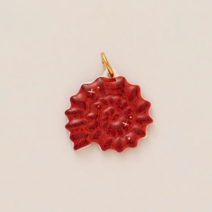 Detail van een rode schelpvormige tassenhanger met sterpatroon en gouden ring