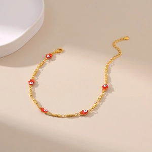 Détail de la chevillère dorée avec breloques Main de Fatma rouges et pendentifs yeux