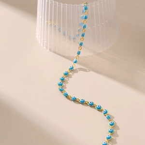 Dettaglio della collana dorata con ciondoli occhio del male blu e bordo con perline
