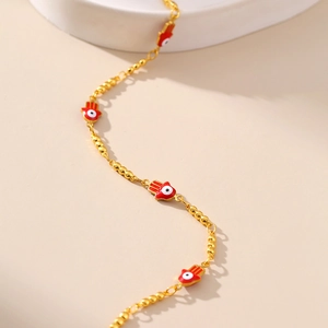 Détail de la chevillère main de Fatma dorée avec charmes œil maléfique rouge et chaîne
