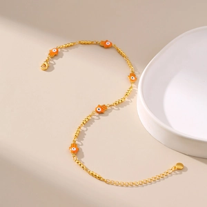 Détail de la chaîne de cheville dorée avec breloques Main de Fatma orange et œil protecteur