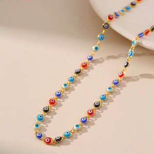 Dettaglio collana a catena dorata con perline colorate a forma di malocchio