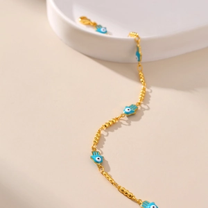 Détail de la chaîne de cheville dorée avec pendentifs main de Hamsa bleue et œil protecteur