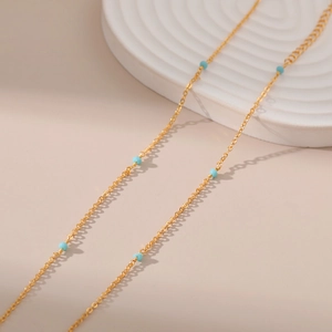 Macro-detail van 18K vergulde minimalistische ketting met kleine turquoise kralen