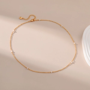 Detail van de minimalistische 18K vergulde ketting met witte kralen en een karabijnsluiting