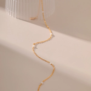 Detail van 18K vergulde minimalistische ketting met delicate witte parel accenten