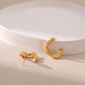 Dettaglio macro di orecchini placcati oro 18K con motivo a rombi in rilievo vintage