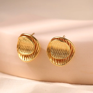 Vintage style layered wavy gold stud earrings with 18K gold plating on a beige pedestal