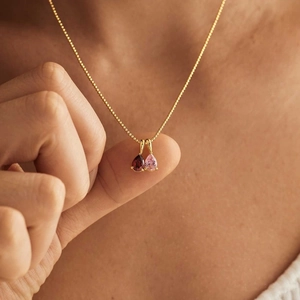 Detailed view of dual water-drop gemstones on a golden ball chain necklace