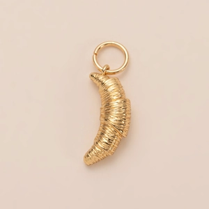 Gedetailleerde macro van een 14K vergulde croissant hanger met fijne textuurdetails