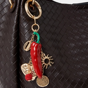 Vue macro d'un charm piment avec détails en métal doré sur un sac à main tissé de luxe