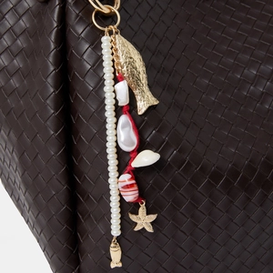 Détail d'un bijou de sac marin avec perles et coquillages sur un sac en cuir tressé