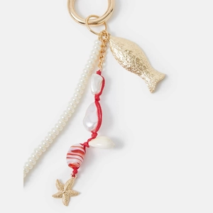 Détail d'un bijou de sac marin avec coquillages, perles, étoile de mer et charms dorés
