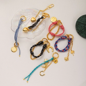 Elegant gold keychain set with colorful braided ropes and assorted charms on white background