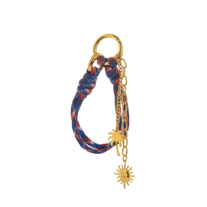 Detail of woven rope keychain with gold coconut tree and smiling sun pendants
