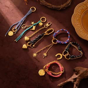 Detail of elegant gold charms and woven rope keychains on a rustic background