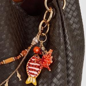 Détail de breloques poisson rouge et crabe orange sur un sac en cuir tressé chic