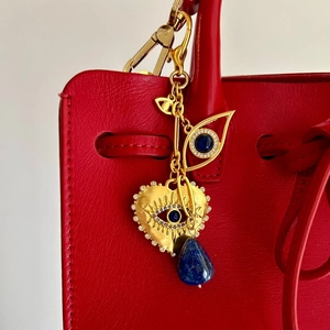 Détail du charme œil porte-bonheur avec pierre bleue sur un sac en cuir rouge