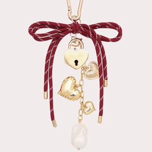 Détail d'un porte-clés à nœud bordeaux avec breloques cœur et perle baroque dorée