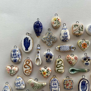 Detail of hand-painted ceramic skull and animal pendants with gold-plated stainless steel loops