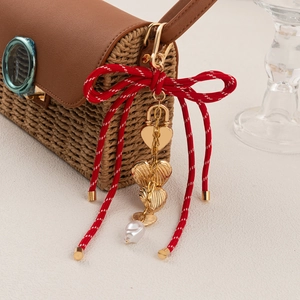 DIY fashion keychain with red polka dot bow and gold heart pendants on a straw bag