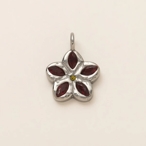 Detalle de colgante de flor con gemas rojas y chapado al vacío de 18K