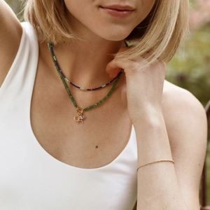 Detail of layered turquoise beaded necklaces with gold horseshoe and portrait pendants