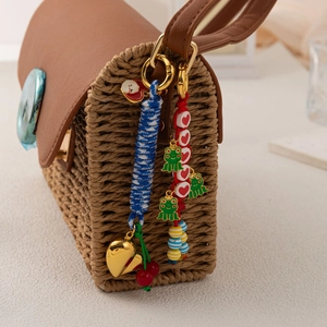 Straw crossbody bag with 18K plated charms featuring hearts, frogs, and cherry accents
