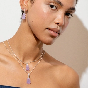Detail of a layered necklace and earrings featuring purple gummy bear charms with zircons