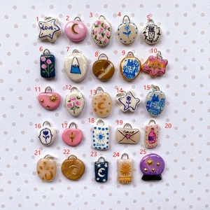 Macro view of 25 unique 18K gold plated enamel flower and moon charms for DIY jewelry