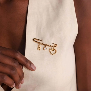 Primer plano de un broche imperdible dorado con colgantes de corazón y opalo