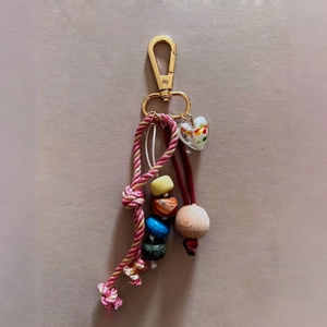 Detail of colorful beaded bag charm with woven rope and transparent heart pendant