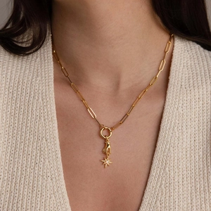 Vista detallada de un collar de cadena de oro con colgante de mano y estrella de ópalo