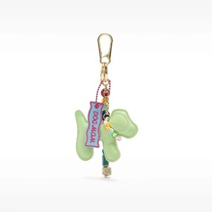 Close-up of a green leather dog charm with gold hardware and pink DOG MOM fabric tag